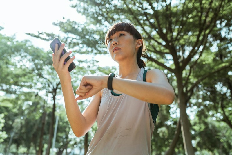 Runner checking fitness tracker and phone outdoors